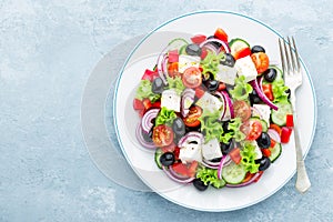 Greek salad of fresh cucumber, tomato, sweet pepper, lettuce, red onion, feta cheese and olives with olive oil