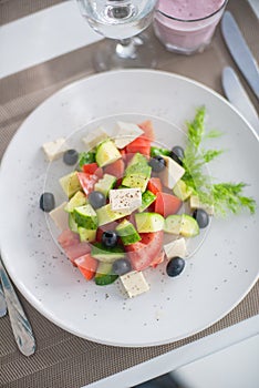 Greek salad of fresh cucumber, tomato, sweet pepper, lettuce, red onion, feta cheese and olives with olive oil