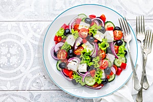 Greek salad of fresh cucumber, tomato, sweet pepper, lettuce, red onion, feta cheese and olives with olive oil