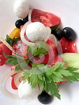 Greek salad of fresh seasonal vegetables with goat cheese and olives close-up.