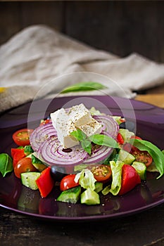 Greek salad with fresh tomato, cucumber, red onion, basil, lettuce, feta cheese, black olives and a Italian herbs