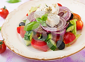 Greek salad with fresh tomato, cucumber, red onion, basil, lettuce, feta cheese, black olives and a Italian herbs