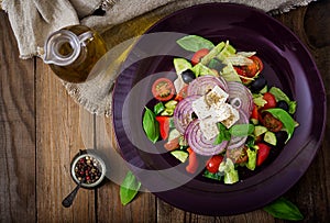 Greek salad with fresh tomato, cucumber, red onion, basil, lettuce, feta cheese, black olives and a Italian herbs