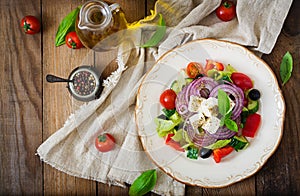 Greek salad with fresh tomato, cucumber, red onion, basil, lettuce, feta cheese, black olives and a Italian herbs