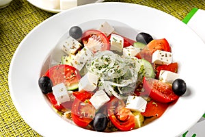 Greek salad, fresh vegetable salad, cheese and black olives in a white plate, top view