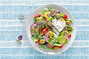 Greek salad. Fresh vegetable salad of cucumbers, tomatoes, olives, onion, bell pepper, feta cheese, lettuce and herbs and dressed