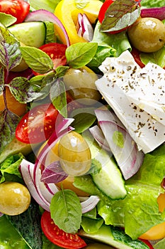 Greek salad. Fresh vegetable salad of cucumbers, tomatoes, olives, onion, bell pepper, feta cheese, lettuce and herbs and dressed