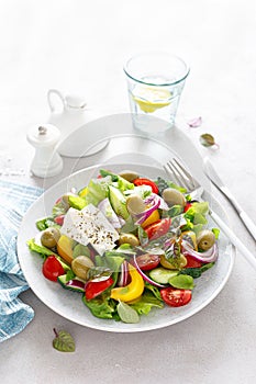 Greek salad. Fresh vegetable salad of cucumbers, tomatoes, olives, onion, bell pepper, feta cheese, lettuce and herbs and dressed