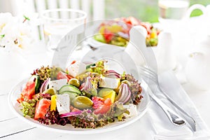 Greek salad. Fresh vegetable salad with tomato, onion, cucumber, pepper, olives, lettuce and feta cheese. Greek salad on plate