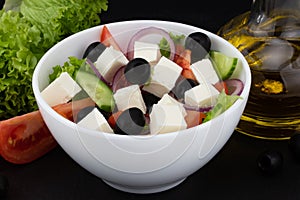 Greek salad with fresh vegetables, feta cheese and black olives on a dark background