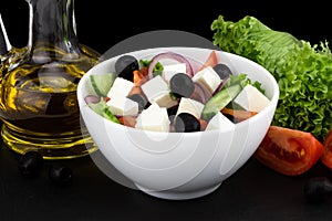 Greek salad with fresh vegetables, feta cheese and black olives on a dark background