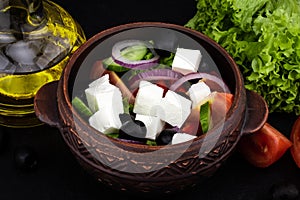 Greek salad with fresh vegetables, feta cheese and black olives on a dark background