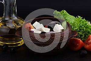 Greek salad with fresh vegetables, feta cheese and black olives on a dark background