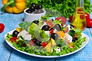 Greek salad with fresh vegetables, feta cheese and black olives on a wooden background