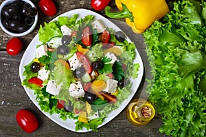 Greek salad with fresh vegetables, feta cheese and black olives on a wooden background