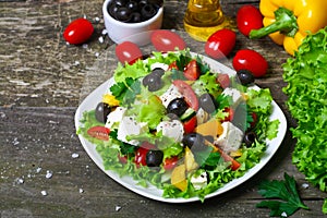 Greek salad with fresh vegetables, feta cheese and black olives on a wooden background