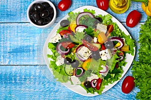 Greek salad with fresh vegetables, feta cheese and black olives on a wooden background