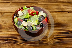 Greek salad with fresh vegetables, feta cheese and black olives on wooden table