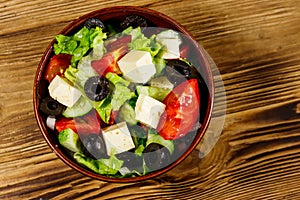 Greek salad with fresh vegetables, feta cheese and black olives on wooden table. Top view