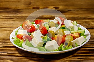 Greek salad with fresh vegetables, feta cheese and green olives on wooden table