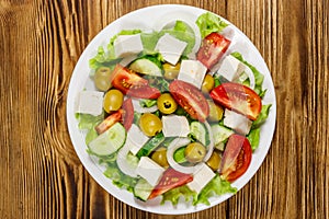 Greek salad with fresh vegetables, feta cheese and green olives on wooden table. Top view