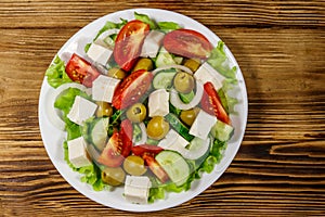 Greek salad with fresh vegetables, feta cheese and green olives on wooden table. Top view