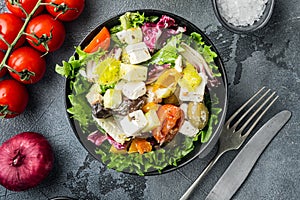 Greek salad with fresh vegetables, feta cheese and olives, on gray background, top view flat lay