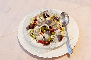 Greek salad with fresh vegetables, feta cheese and olives on table