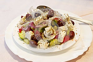 Greek salad with fresh vegetables, feta cheese and olives on table