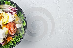 Greek salad with fresh vegetables, feta cheese and olives, on white background, top view flat lay  with copy space for text