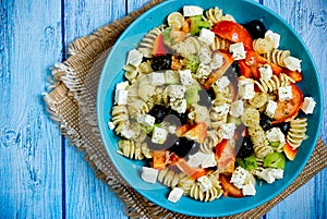 Greek salad with fresh vegetables, feta cheese, pasta and black olives