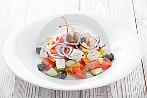 Greek salad with fresh vegetables, olives and feta cheese on wooden background close up