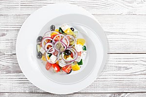 Greek salad with fresh vegetables, olives and feta cheese on wooden background close up