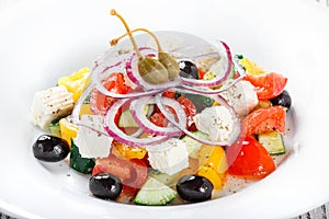 Greek salad with fresh vegetables, olives and feta cheese on wooden background close up