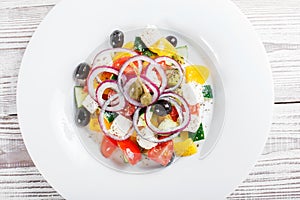 Greek salad with fresh vegetables, olives and feta cheese on wooden background close up