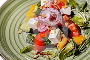 Greek salad on a green plate isolated on a white background