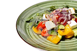 Greek salad on a green plate isolated on a white background