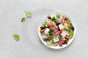 Greek salad with greens, olives and feta chesse on a white plate