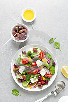Greek salad with greens, olives and feta chesse on a white plate