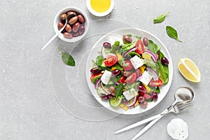 Greek salad with greens, olives and feta chesse on a white plate