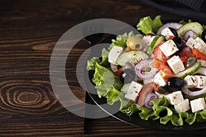 greek salad with olives and capers on a black plate