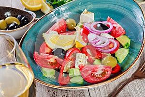 Greek salad of organic vegetables with tomatoes, cucumbers, red onion, olives, feta cheese and glass of wine