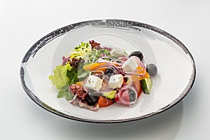 Greek salad in a plate isolated on a white background