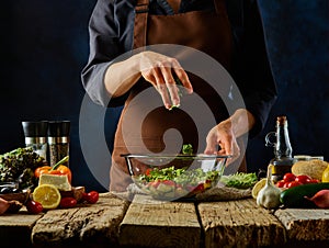 Greek salad preparation process. In a glass bowl, all the ingredients for the salad are cut into pieces. The cook mixes them up.