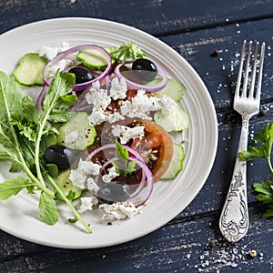 Greek salad - salad with tomatoes, cucumbers, olives and feta cheese on a white plate