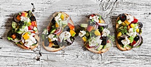 Greek salad style bruschetta on a wooden rustic board, top view. Delicious appetizers