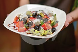 Greek salad. Tasty and healthy vegetarian meal. Eating out in restaurant, service.