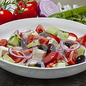 Greek Salad in. White Bowl with Ingredients Behind