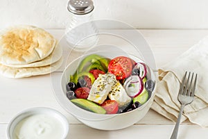 Greek salad on a white wooden background. Tomatoes, peppers, olives, cheese, onions. Healthy eating. Diet. Vegetarian food