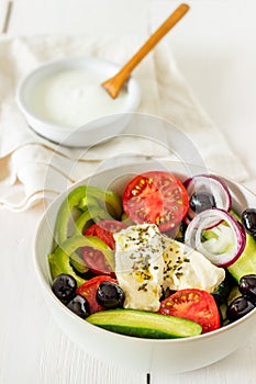 Greek salad on a white wooden background. Tomatoes, peppers, olives, cheese, onions. Healthy eating. Diet. Vegetarian food